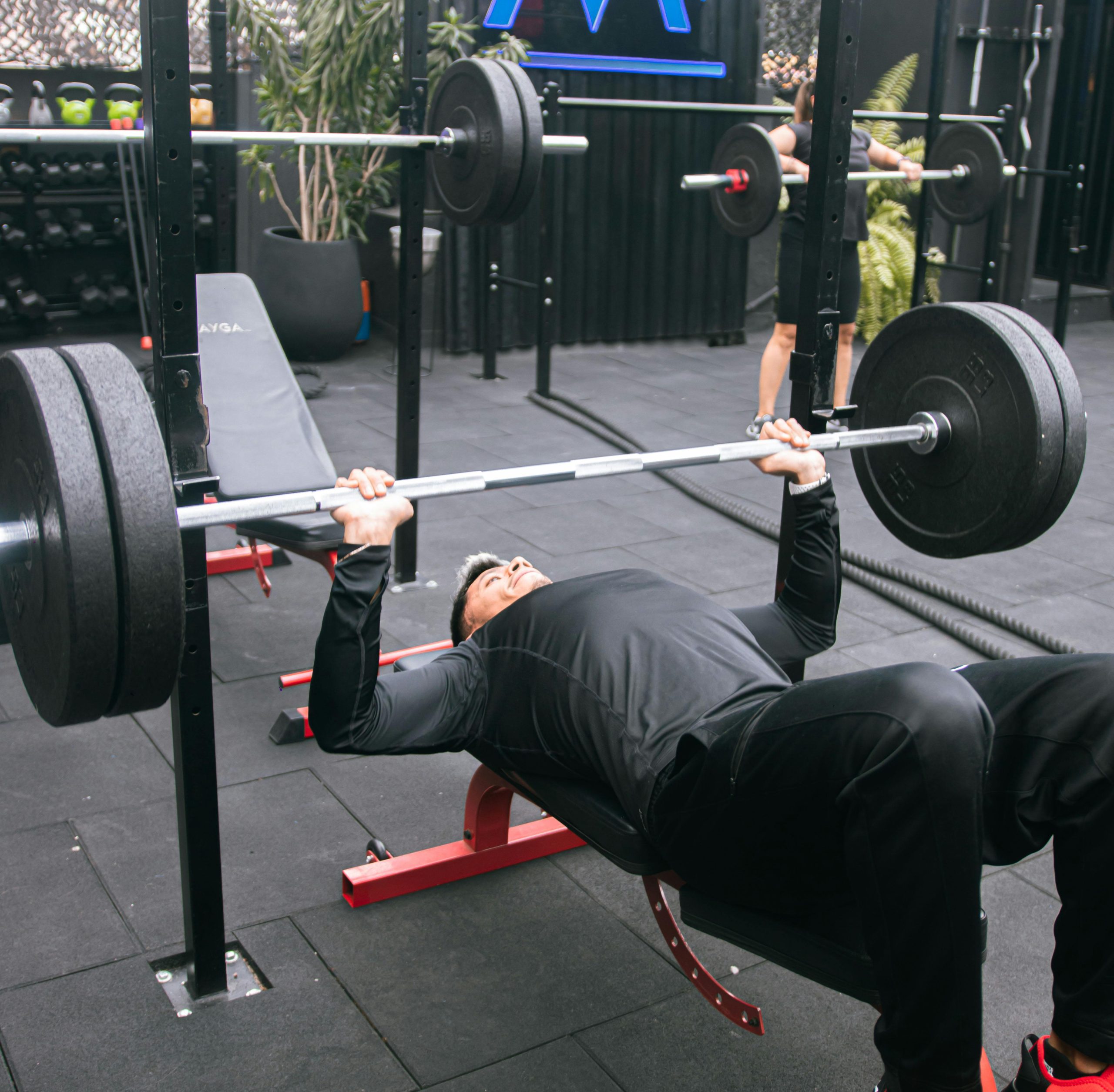 Adult man performing bench press exercise in a gym in Mexico City, emphasizing strength and fitness.